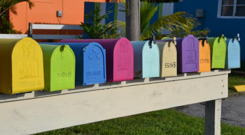 horizontal line of brightly colored mail boxes all in a row on a wood platform