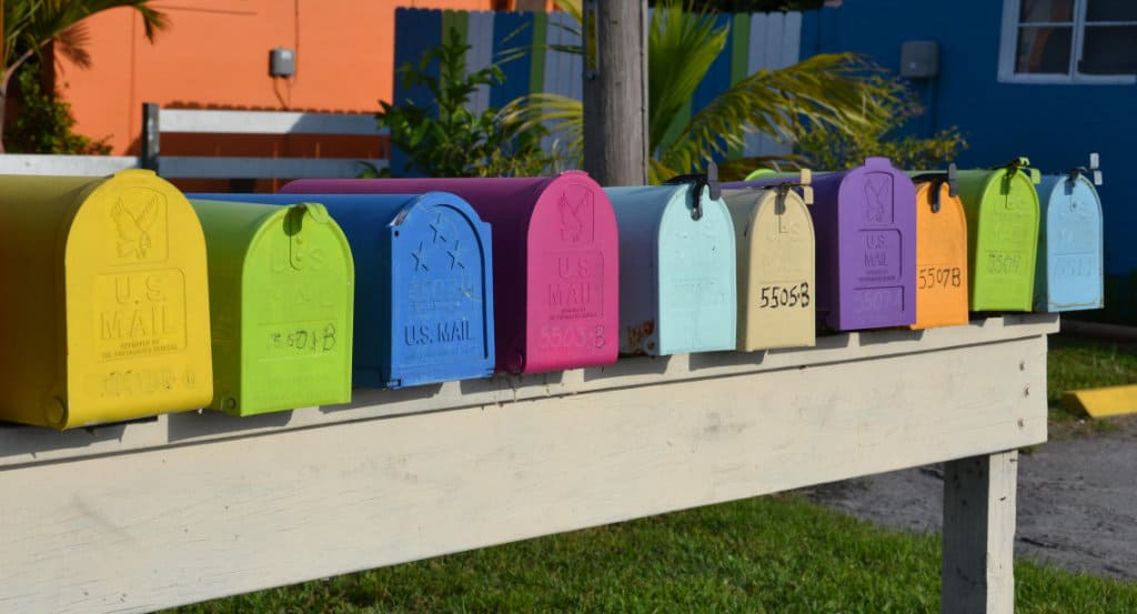 horizontal line of brightly colored mail boxes all in a row on a wood platform